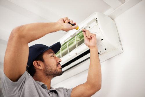 Air conditioner, man and electrical machine work with person in a home with ac repair. Maintenance,